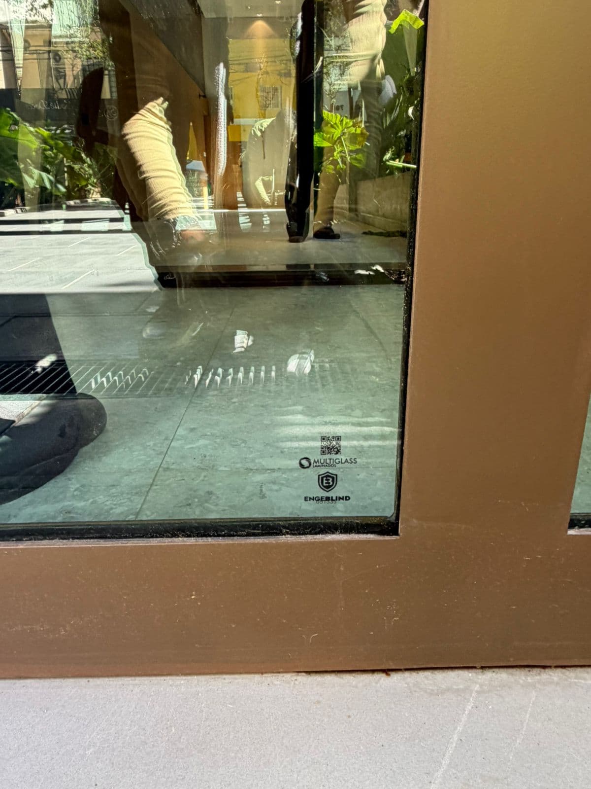 Detalhe de janela blindada com caixilho bronze e selo Engeblind · instalação comercial